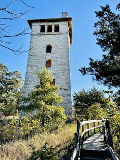 a tall tower with a clock on it's side in the middle of trees