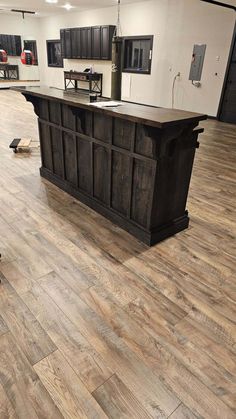 an empty kitchen with wooden floors and black cabinets