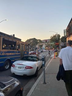 a man standing on the side of a road next to a parked car and a bus