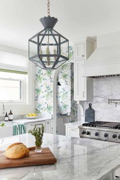 a kitchen with marble counter tops and white cabinets, along with a hanging light fixture