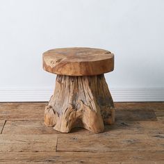 a wooden stool sitting on top of a hard wood floor next to a white wall