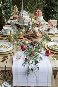 a table set for christmas dinner with plates, silverware and other holiday foods on it