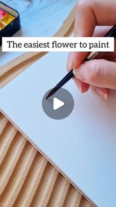 a person holding a pen and writing on paper with the words the easier flower to paint