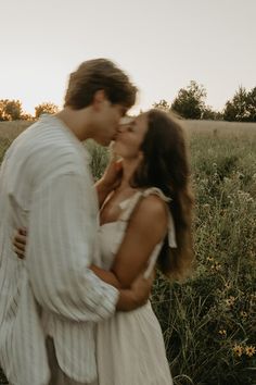 a man and woman are kissing in a field