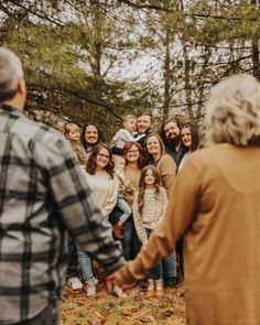 a group of people standing around each other in the woods with one person holding his hand