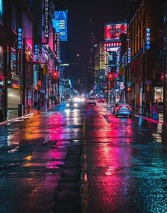 a city street at night with cars and neon lights