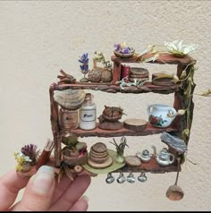 a hand holding a miniature shelf with various items on it