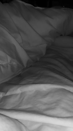 an unmade bed with white sheets and pillows