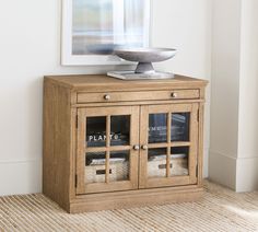 a wooden cabinet with glass doors and a bowl sitting on top of it next to a wall