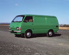 a green van parked on the side of a road in front of a dry grass field