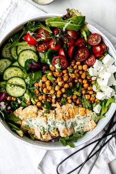 a salad with chicken, tomatoes, cucumbers and chickpeas in it