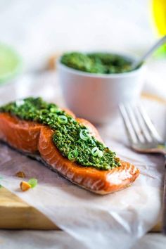 two salmon fillets with pesto on top, next to a bowl of broccoli