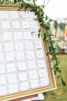 the seating chart is set up with greenery on it for an outdoor wedding ceremony