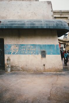 an old building with graffiti on it and people walking by