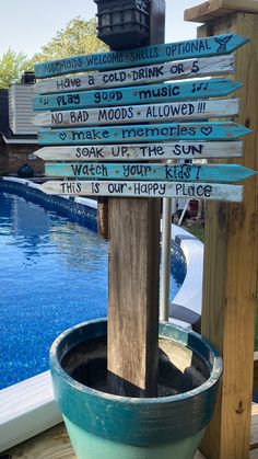 a wooden sign sitting on the side of a swimming pool next to a blue tub