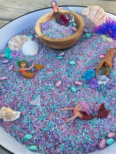 a cake decorated with purple sprinkles and little mermaid figurines