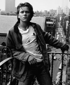 a man standing on top of a balcony next to a cityscape with tall buildings in the background