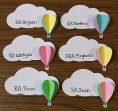 four hot air balloons with name tags on them sitting on top of a wooden table