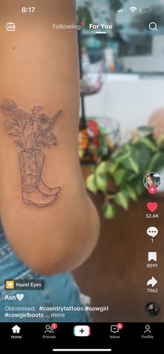 a tattoo on the back of a woman's leg with flowers in a boot