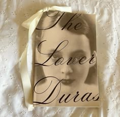 the lover's duras book is laying on a white lace covered bed sheet