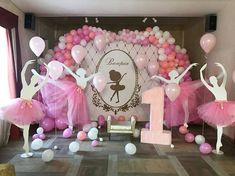 some pink and white balloons are in the air with ballerinas on display behind them