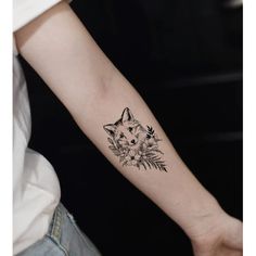 a woman's arm with a small tattoo of a fox and flowers on it