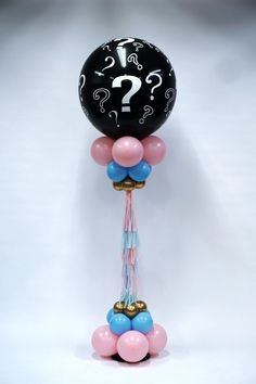 balloon with question mark on it and tassels attached to the balloons are pink, blue, and gold