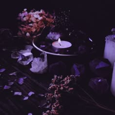 candles, rocks and crystals on a table with purple lighting in the dark night time