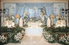 an elaborately decorated wedding stage with flowers and greenery on the sides, surrounded by candles