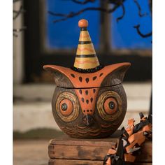 an owl shaped container with a party hat on it's head sitting on top of some wood