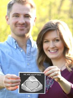 a man and woman holding up a card with the words we are adopted on it