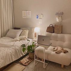 a laptop computer sitting on top of a white couch next to a bed in a bedroom