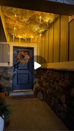 a blue front door with lights hanging from it's ceiling and a wreath on the side