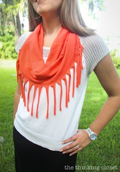 a woman standing in the grass wearing an orange and white scarf with dripping paint on it