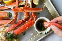 a person dipping crab legs into a small bowl