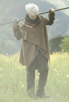 an old woman with white hair holding a stick in her hand while standing in a field