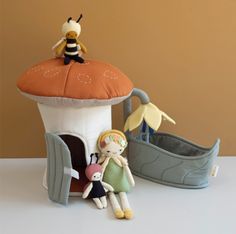 a small doll sitting on top of a mushroom house next to a baby's crib