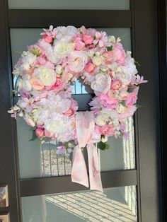 a wreath with pink and white flowers hanging from the front door