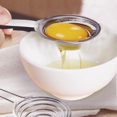 an egg being whisked into a white bowl with a measuring spoon on top