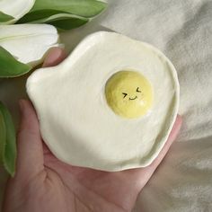 a hand holding an egg shell with a smiley face painted on it's side