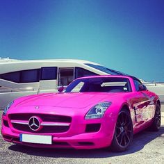 a pink sports car parked in front of a boat