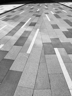 a black and white photo of an empty street with lines on the pavement in front of it