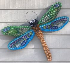 a colorful dragon made out of glass beads sitting on top of a white wooden wall