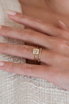 a woman's hand with two wedding rings on her left and the other hand holding an engagement ring