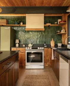 a kitchen with wooden cabinets and green tile backsplashing on the wall above the stove