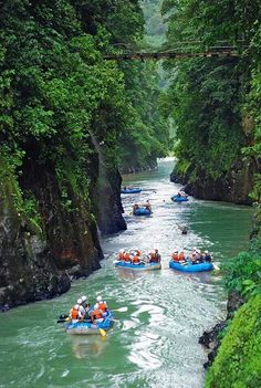 several people are rafting down a narrow river