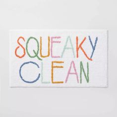 a white door mat with the words sqeaky clean written in multicolored letters