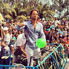 a man riding on the back of a blue bike next to a crowd of people