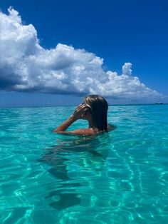 a woman swimming in the ocean with her hand on her head and looking out to sea