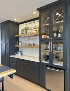 a kitchen with black cabinets and stainless steel appliances in the center, along with shelves that hold wine glasses